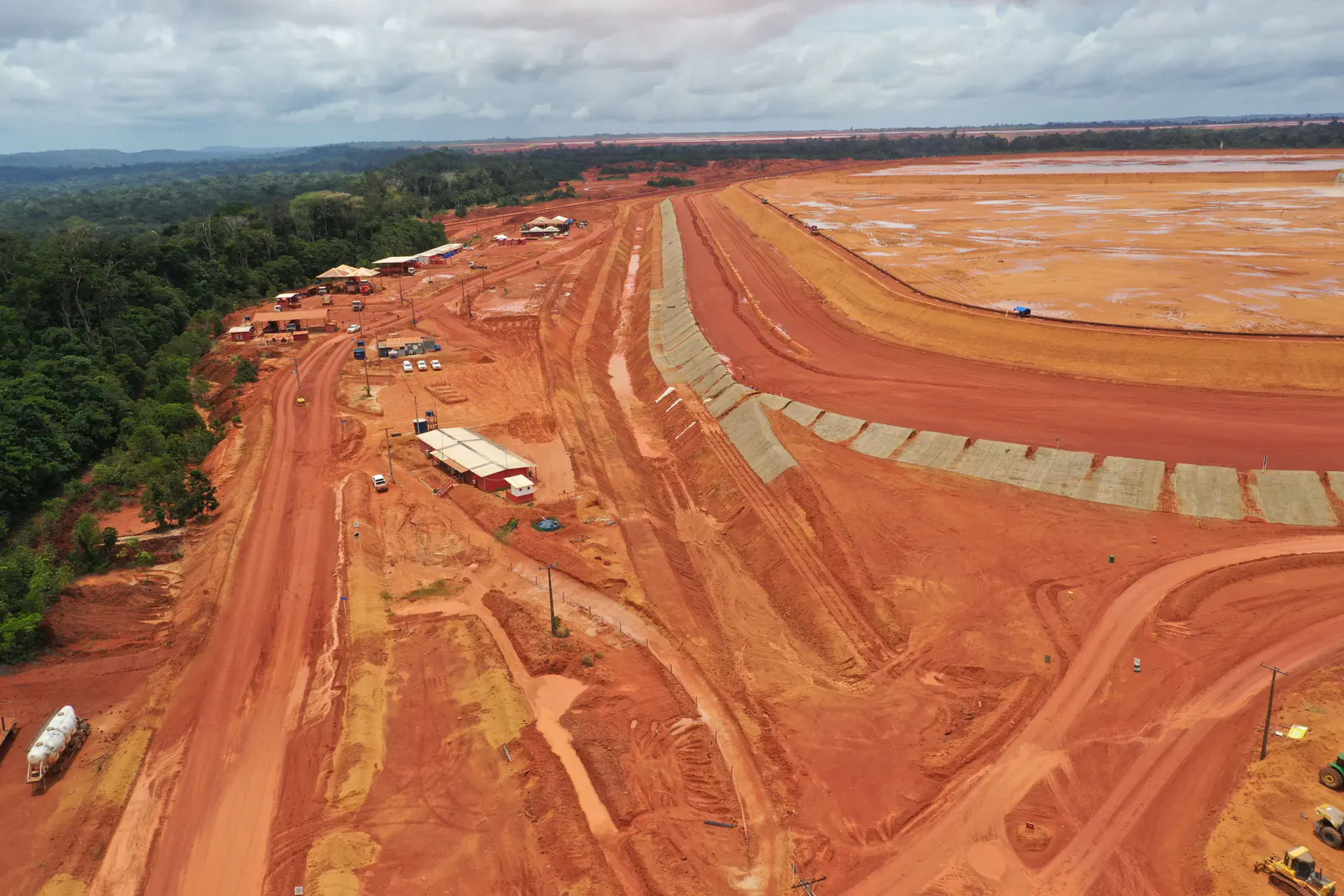 Vista aérea dos taludes em bermas da barragem, com o reservatório ao fundo