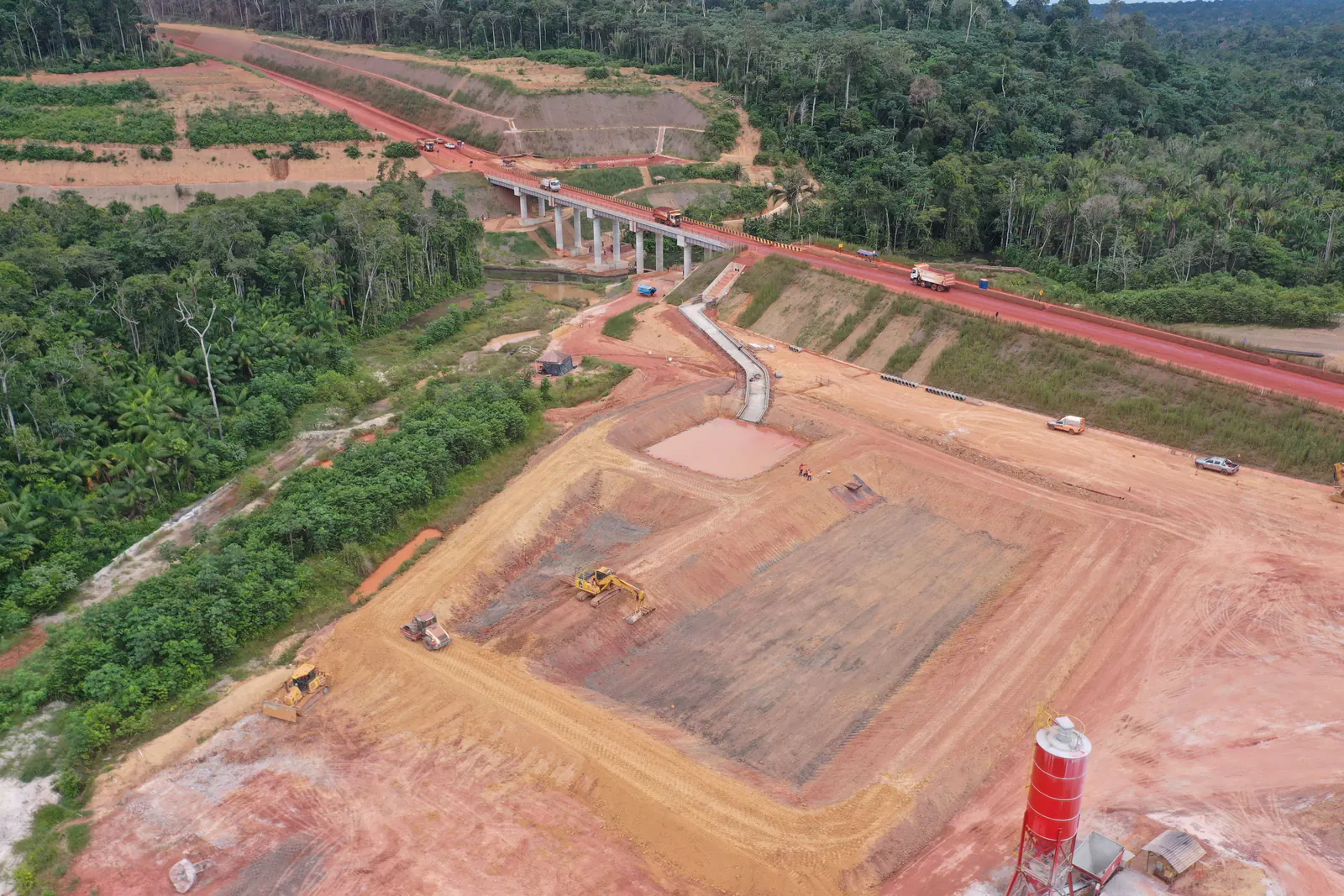 Vista aérea de trecho da estrada com a ponte ao fundo e área de apoio em primeiro plano