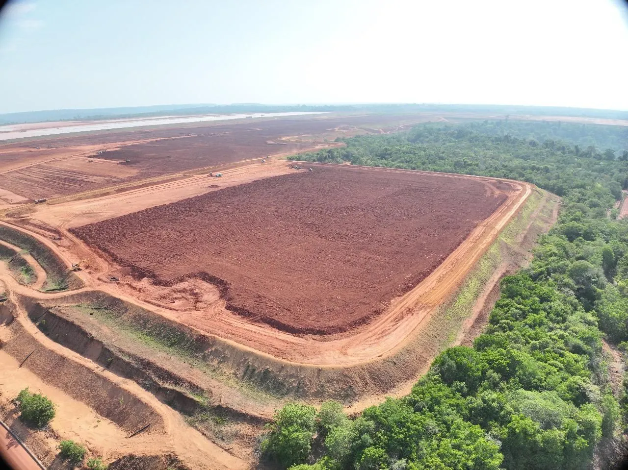 Área da barragem fechada, cercada por floresta, vista do alto