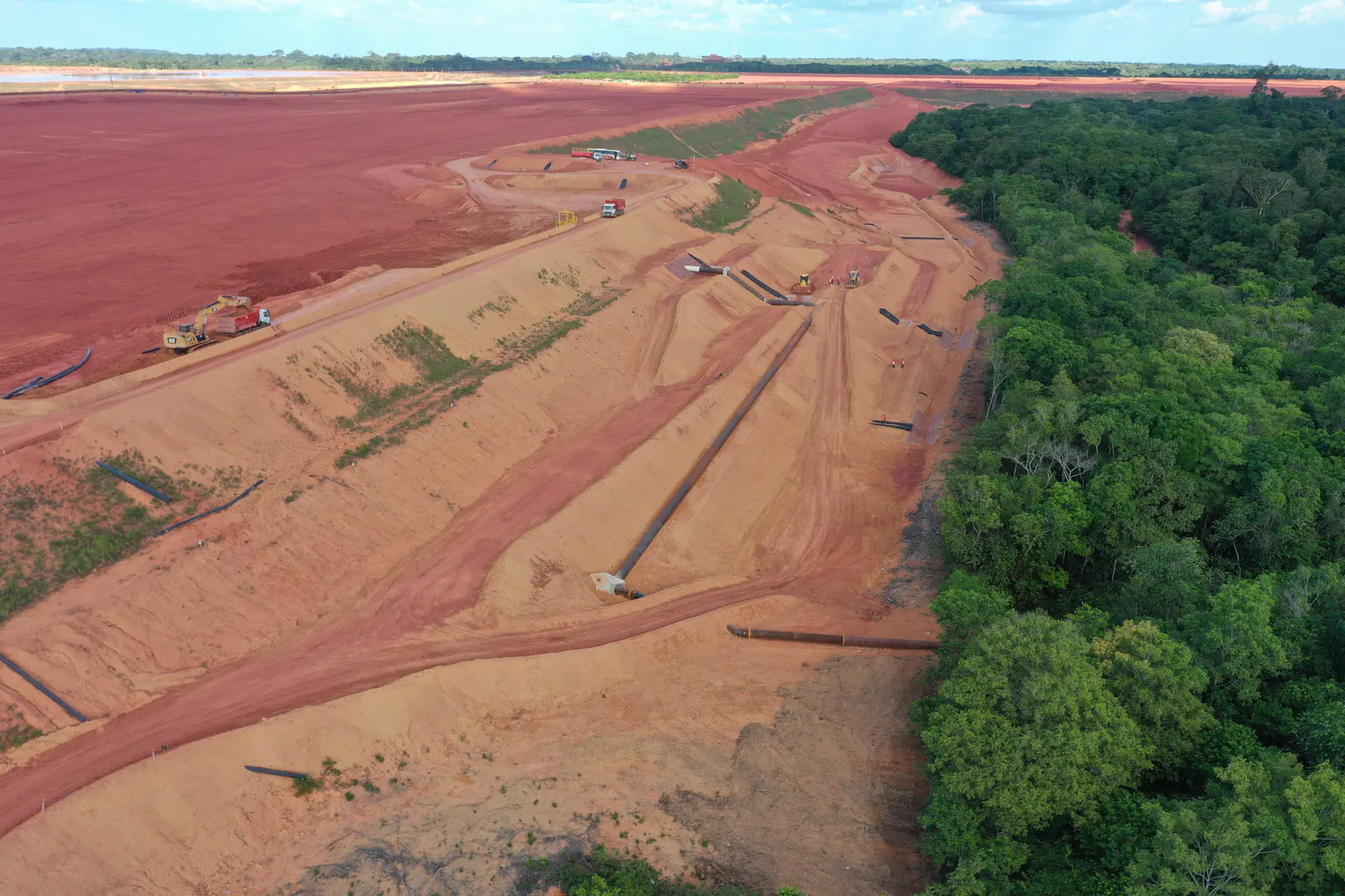 Vista aérea de taludes e canais de drenagem na borda da floresta