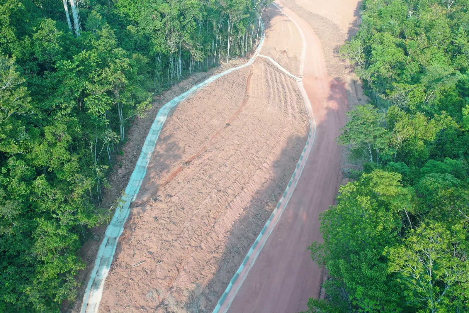 Talude conformado com canaleta de concreto na borda, em clareira na floresta
