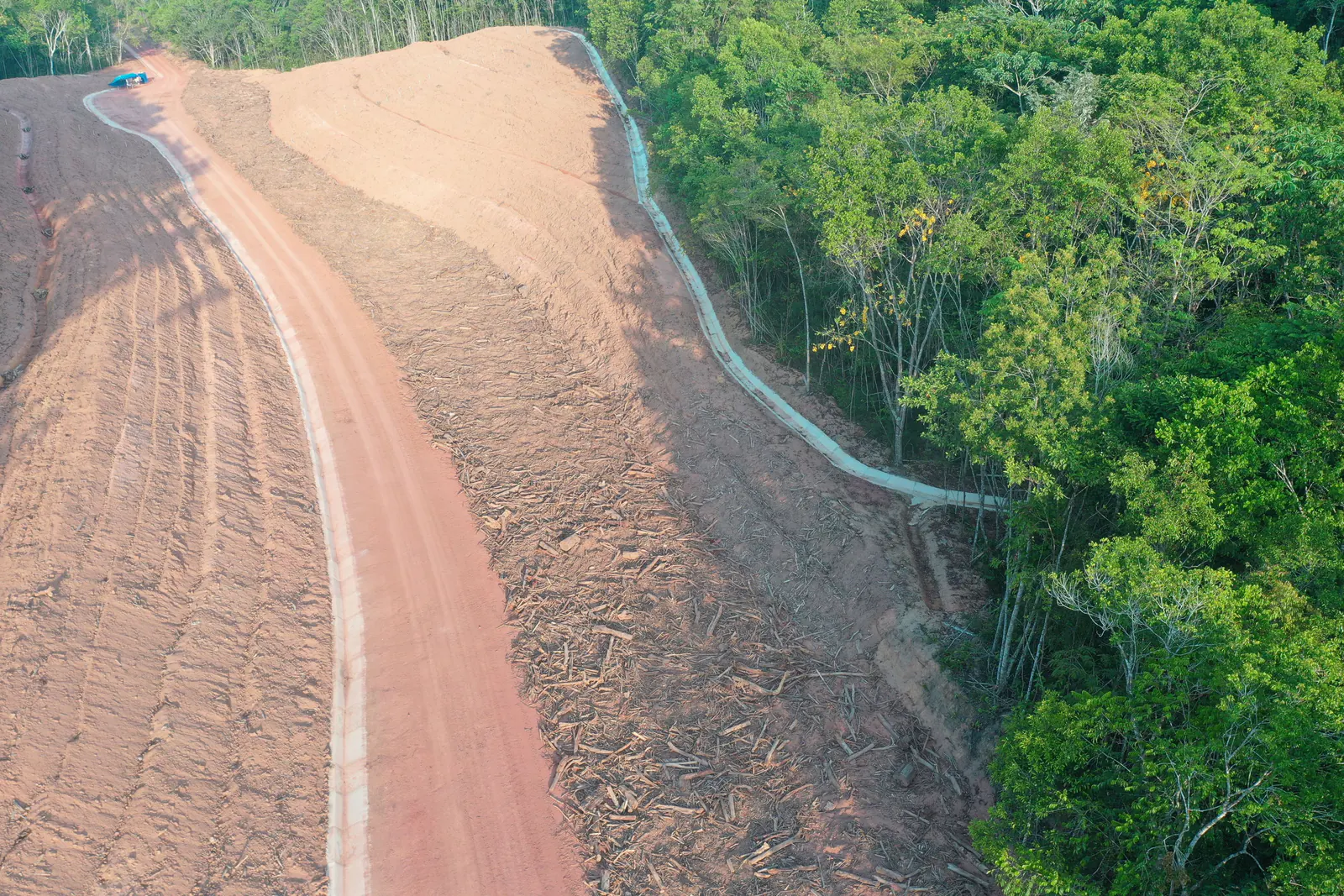 Talude em bancadas visto de cima, com canaleta lateral e mata ao redor